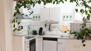 A modern kitchen with white cabinets, a dishwasher, a coffee maker, and potted plants. - Casa Schalkenmehren Grande (Schalkenmehren)