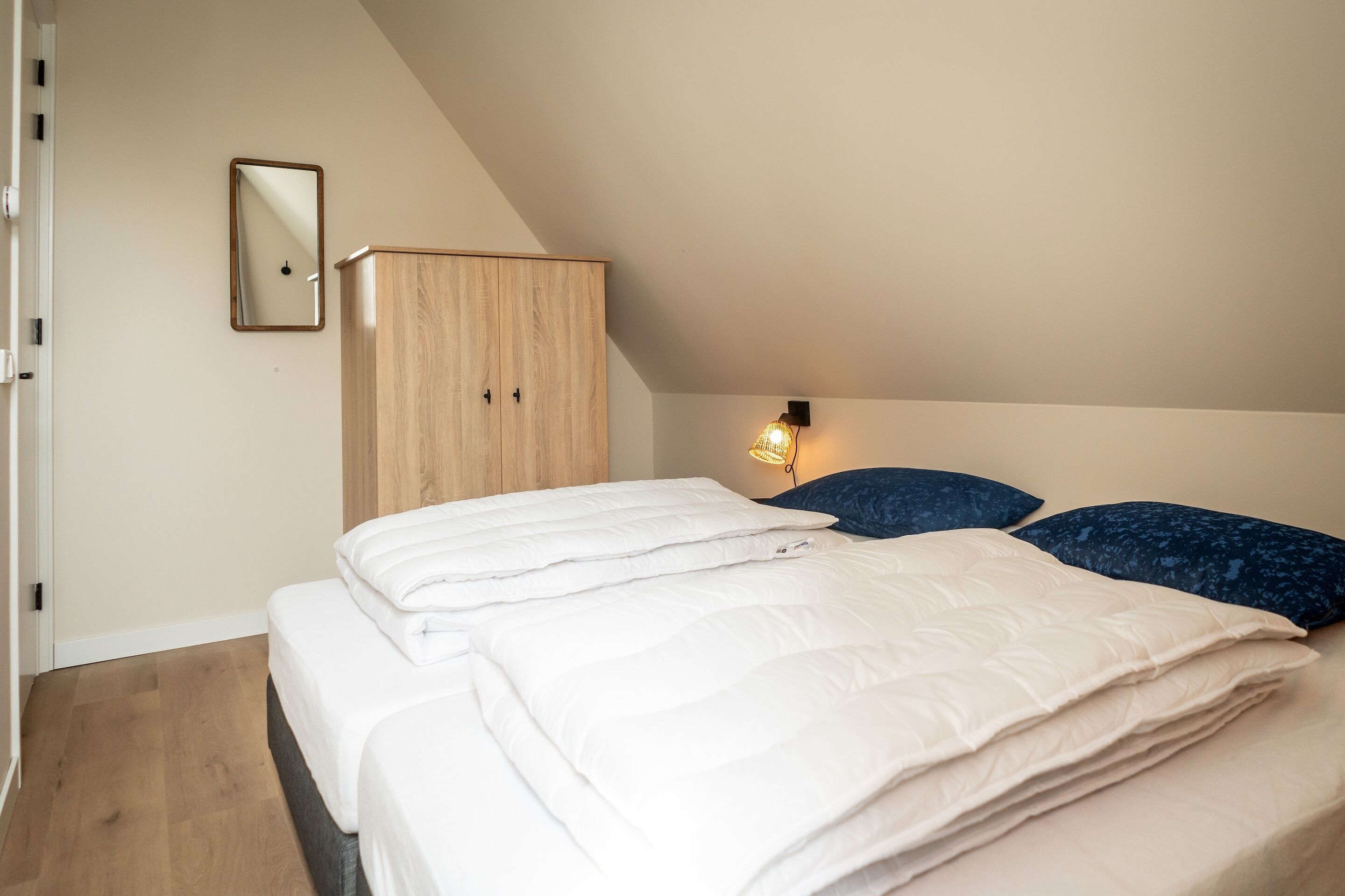 Ein Schlafzimmer mit Bett, Kleiderschrank, Spiegel und einer Wandleuchte.