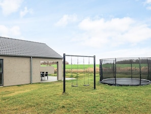 A house with a swing set and a trampoline in the backyard. - 5 Star Holiday Home in Otterup (Otterup)