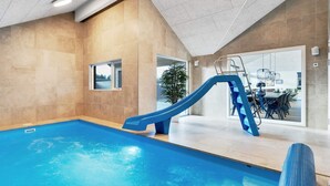An indoor swimming pool with a blue slide, a view of the dining area, and a large window. - 5 Star Holiday Home in Otterup (Otterup)