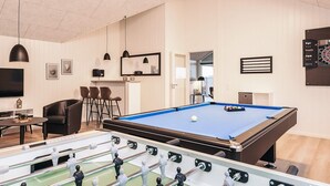 A pool table with a foosball table in front, a TV, and framed pictures on the wall. - 5 Star Holiday Home in Otterup (Otterup)