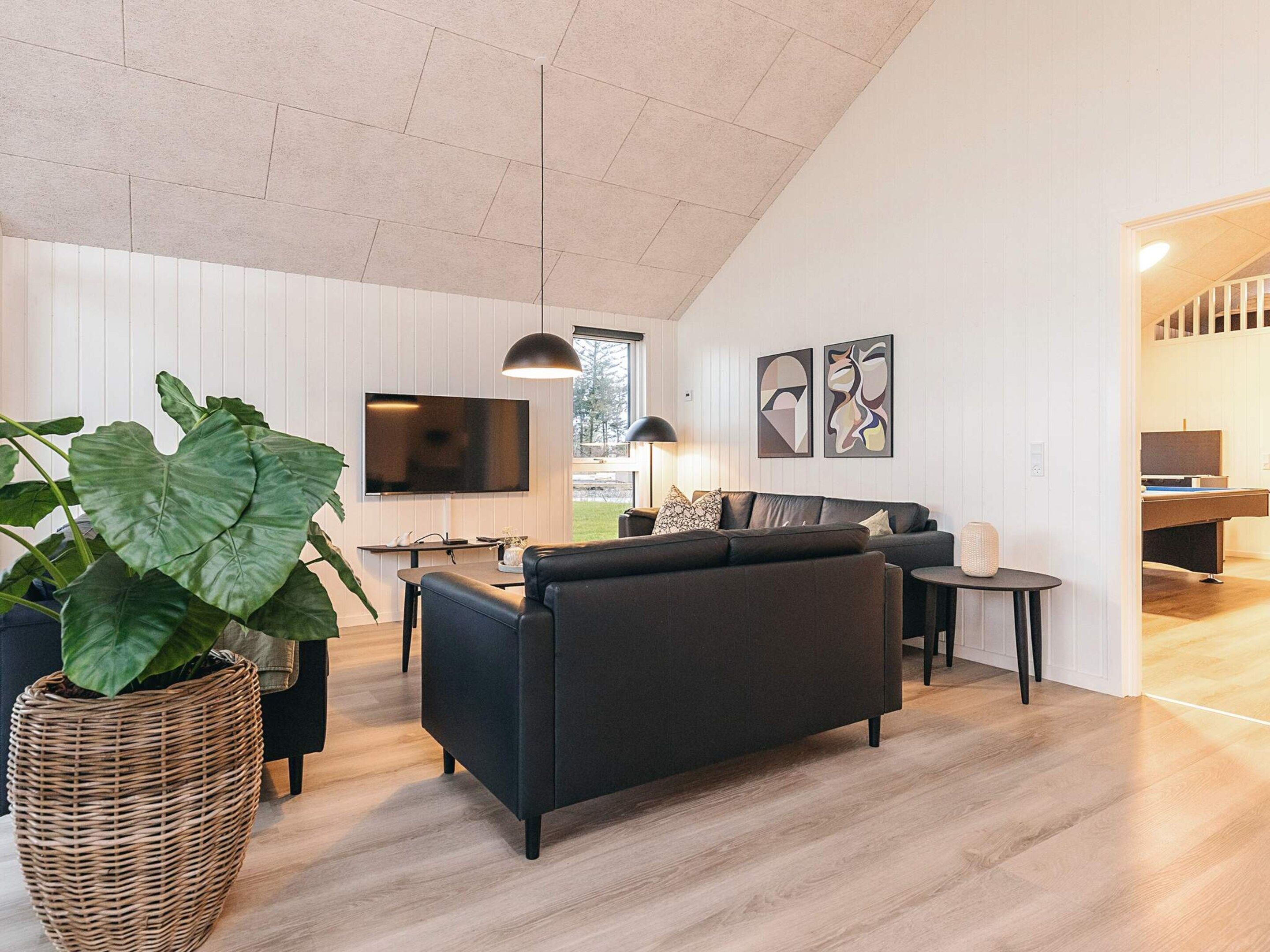A modern living room with a sofa, a dining table, and a large plant.