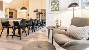 A modern living room with a sofa, ottoman, and dining area with chairs and a table. - 5 Star Holiday Home in Otterup (Otterup)