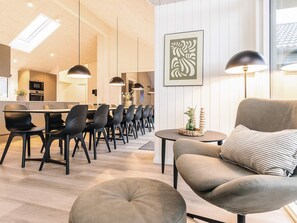 Un salon moderne comprenant un canapé, un pouf et un coin repas avec des chaises et une table.
