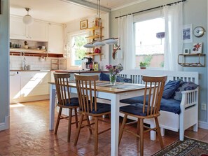 A dining area with a white table, four wooden chairs, a vase with flowers, and a bench with cushions. - 4 Star Holiday Home in Visby (Visby)