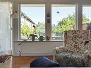 A room with a large window, a chair with floral upholstery, a radiator, and a potted plant. - 4 Star Holiday Home in Visby (Visby)