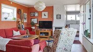 Olohuone, jossa on punainen sohva, kuviollinen nojatuoli, televisio ja koristeellinen kattovalaisin.