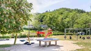 A playground with a slide, swings, and a ping pong table. - Holiday Home in Waxweiler With Pool Access (Waxweiler)