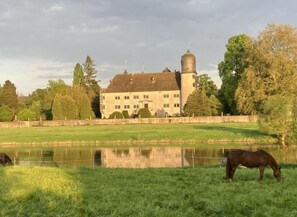 A large, historic building with a moat and horses grazing nearby. - Holiday Apartment Loft (Hehlen)