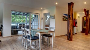 Een eetgedeelte met een tafel, stoelen, een trap en een houten pilaar.
