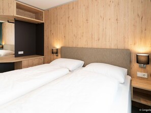 A hotel room with two single beds, wooden panel walls, and wall-mounted reading lamps. - Holiday Apartment in Gerlitzen With Wellness Area (Treffen)
