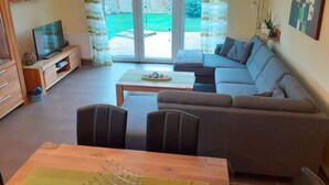 A living room with a sofa, a TV, and a dining table. - Holiday Home Manders (Wangerland)