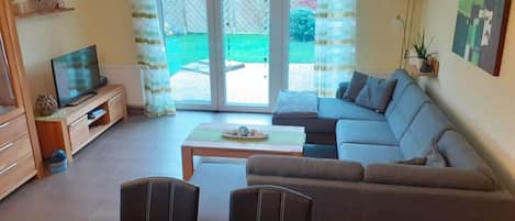 A living room with a sofa, a TV, and a dining table.