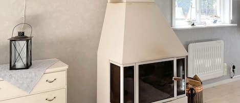 A room with a white fireplace, a window with a view of sailboats, a chandelier, and a lantern on a dresser.