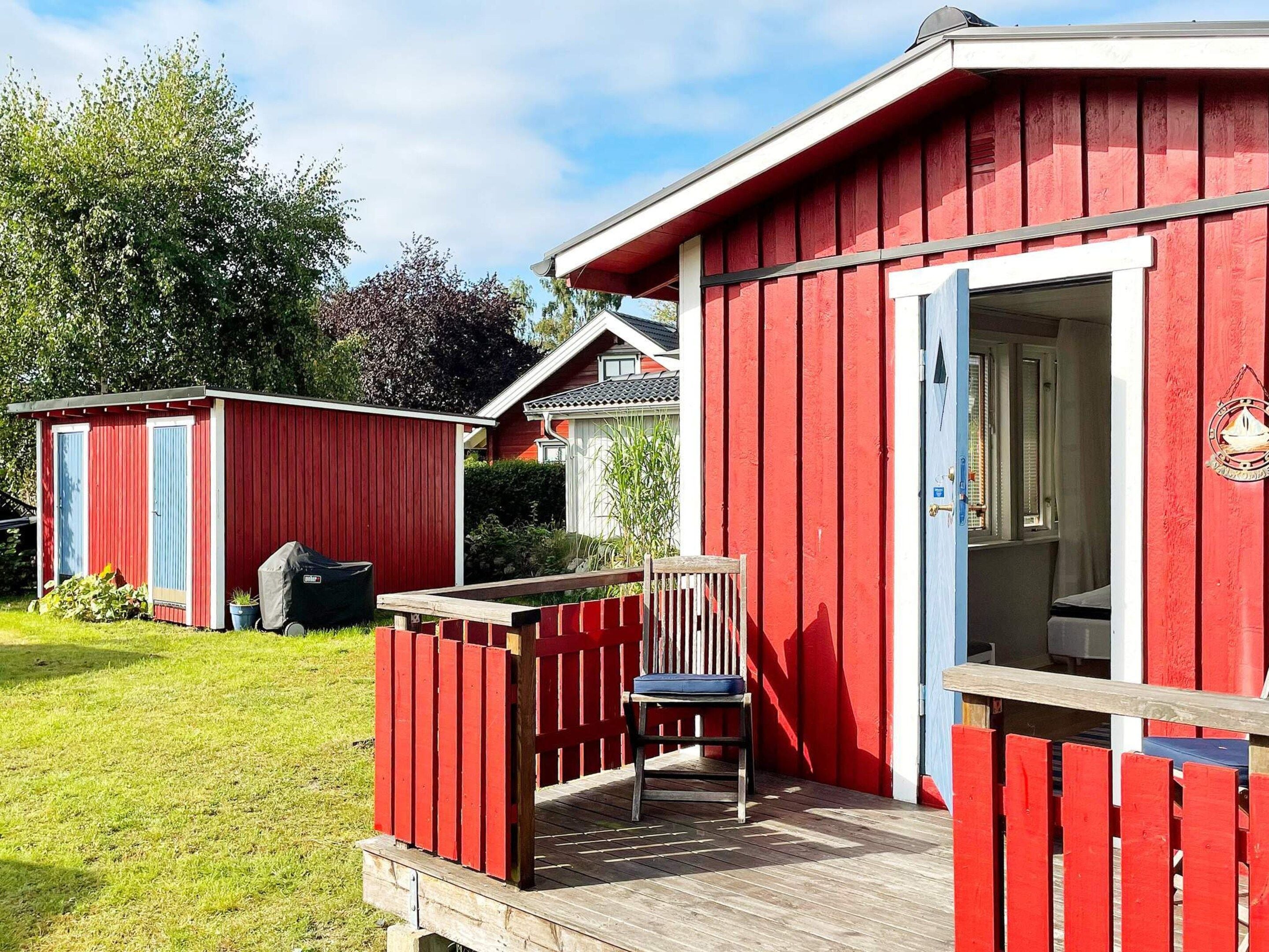 A red wooden building with a porch and a chair.