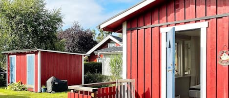 A red wooden building with a porch and a chair.