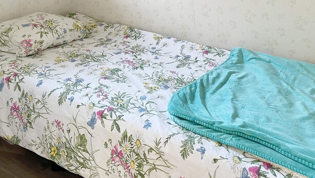 A single bed with a floral bedspread and a teal blanket. - 4 Star Holiday Home in Solvesborg (Sölvesborg)