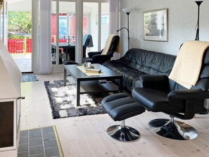 A modern living room with a black leather sofa, a black leather chair, a glass coffee table, and a floor lamp.