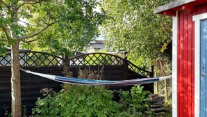A hammock between trees, a wooden fence, and a red and blue shed. - 4 Star Holiday Home in Solvesborg (Sölvesborg)