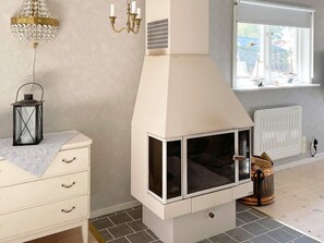 A room with a white fireplace, a window with a view of sailboats, a chandelier, and a lantern on a dresser.