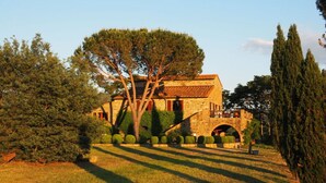 A stone building with a tiled roof, surrounded by well-maintained hedges and trees. - Holiday Apartment Casa Felicita (Gavorrano)