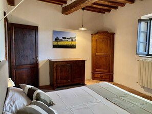 A bedroom with a bed, wooden wardrobe, and a painting on the wall. - Holiday Apartment Casa Felicita (Gavorrano)