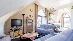 Ein modernes Wohnzimmer im Loft-Stil mit Fernseher, Sofa und Essbereich.