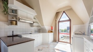 Eine moderne Küche mit weißen Schränken, einer Marmorarbeitsplatte und einem großen Fenster mit Blick ins Freie.