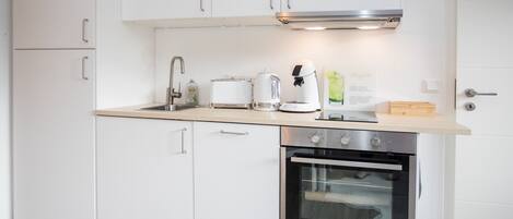 A modern kitchen with white cabinets, a stainless steel oven, a coffee maker, and a toaster.