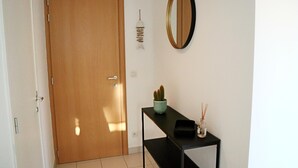 A hallway with a wooden door, a small table with a cactus and a diffuser, and a mirror on the wall. - Apartment in Nieuwpoort Near the Beach (Nieuwpoort)