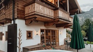 A wooden chalet with a balcony, a hot tub, and outdoor seating. - Chalet Alpin Comfortable Holiday Residence (Bayrischzell)