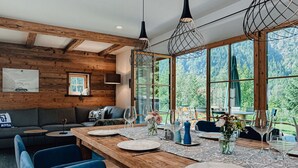 A dining area with a wooden table set for six, surrounded by blue chairs. - Chalet Alpin Comfortable Holiday Residence (Bayrischzell)