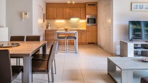 Eine moderne Küche mit Holzausstattung, einem Backofen und einem Essbereich mit Tisch und Stühlen.