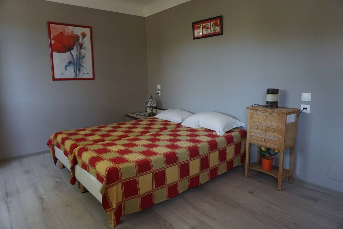 A bedroom with a bed, nightstand, lamp, dresser, and a framed picture on the wall.