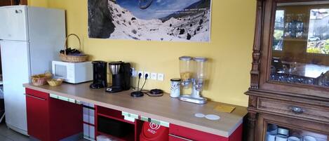Una cocina equipada con refrigerador, microondas, cafetera, licuadora y un cartel con la imagen de un ciclista de montaña.