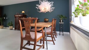 Un comedor con una mesa y sillas de madera, una lámpara decorativa en el techo y plantas en macetas.