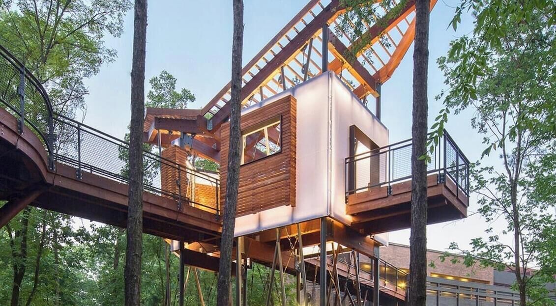 A treehouse with a wooden exterior, a balcony, and a window.