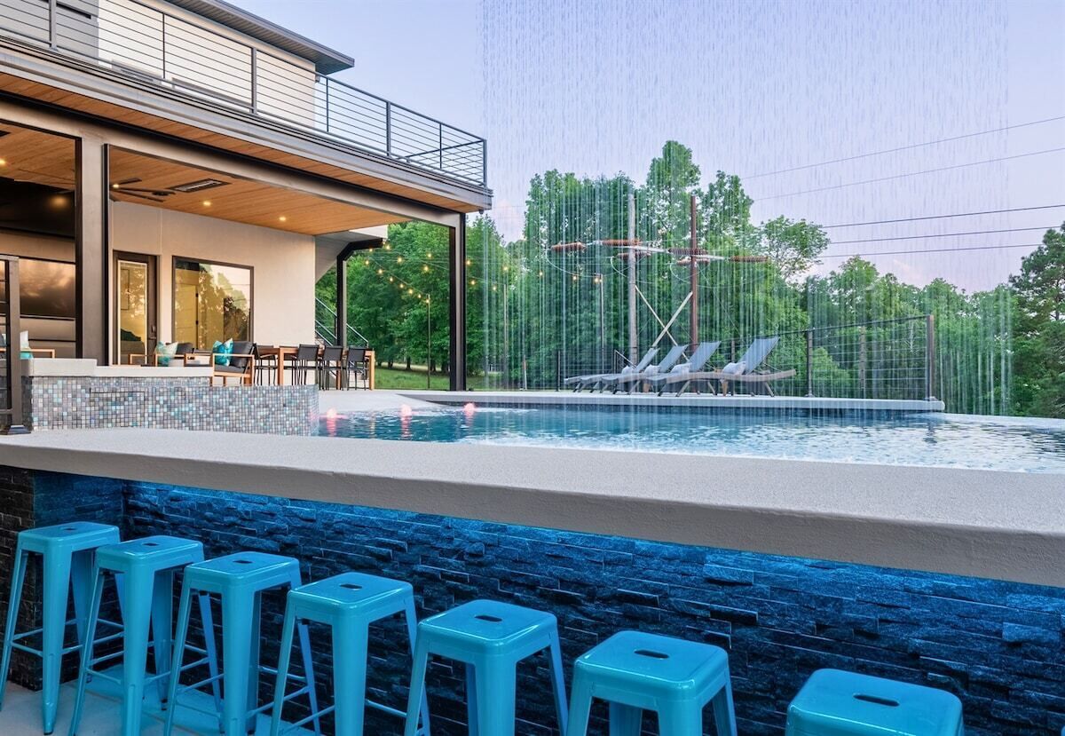 A modern outdoor pool area with a covered seating area and a bar.