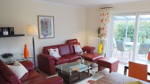 A living room with red leather sofas, a glass coffee table, and a wooden side table. - "landlust" Modern Retreat (Kellenhusen)