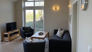 A living room with a TV, two sofas, a coffee table, and large windows. - Northern Light House (Kosel)