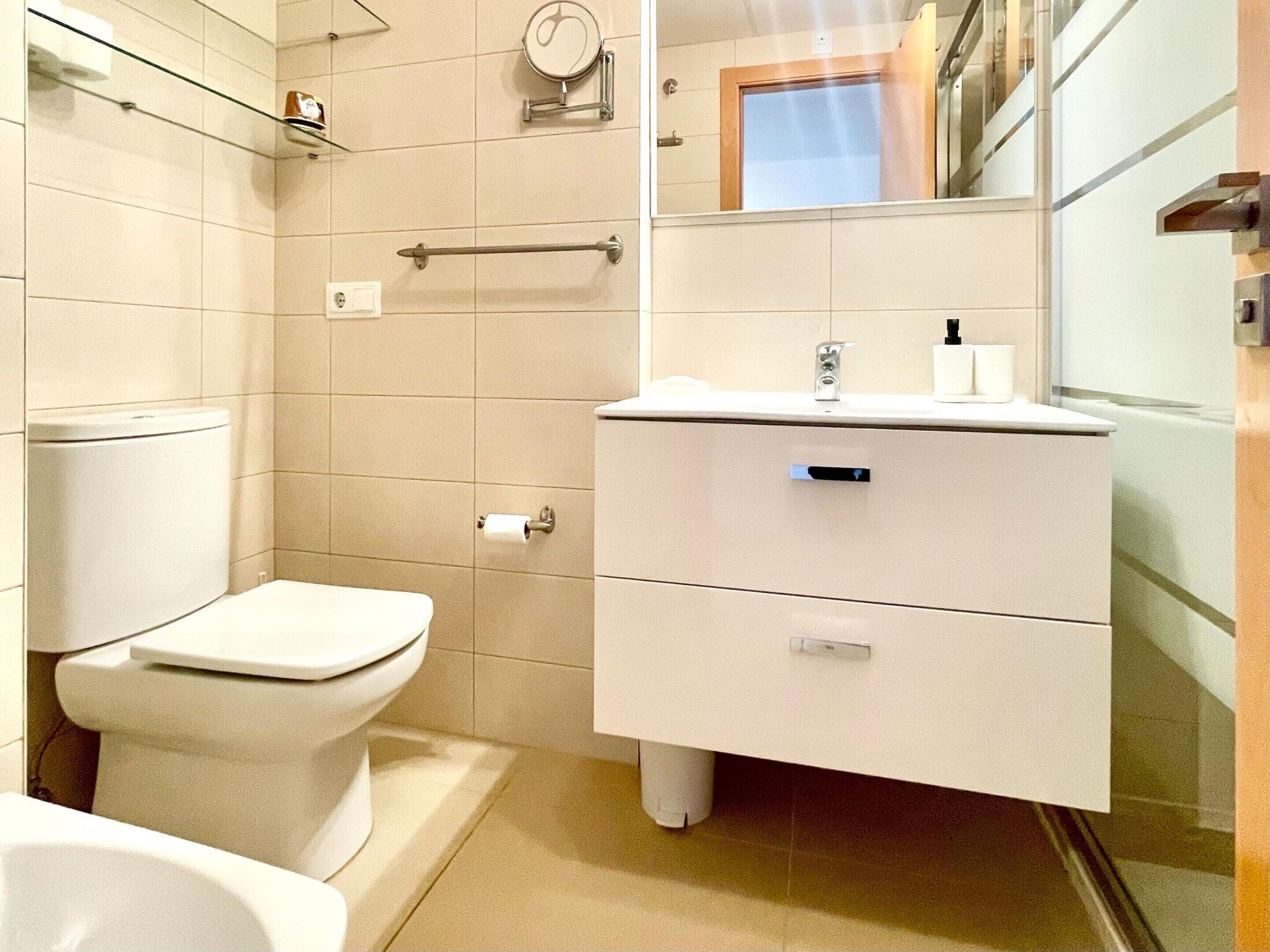 Un bagno moderno con il water, una doccia e un mobile lavabo con specchio.