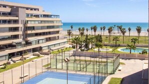 Un hotel de varios pisos con piscina, palmeras y vista a la playa.