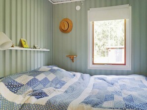 A room with a bed, a window, a hat on the wall, and a shelf with books. - 4 Star Holiday Home in Grisslehamn (Grisslehamn)