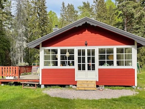 A red wooden cabin with white trim, large windows, and a small porch. - 4 Star Holiday Home in Grisslehamn (Grisslehamn)