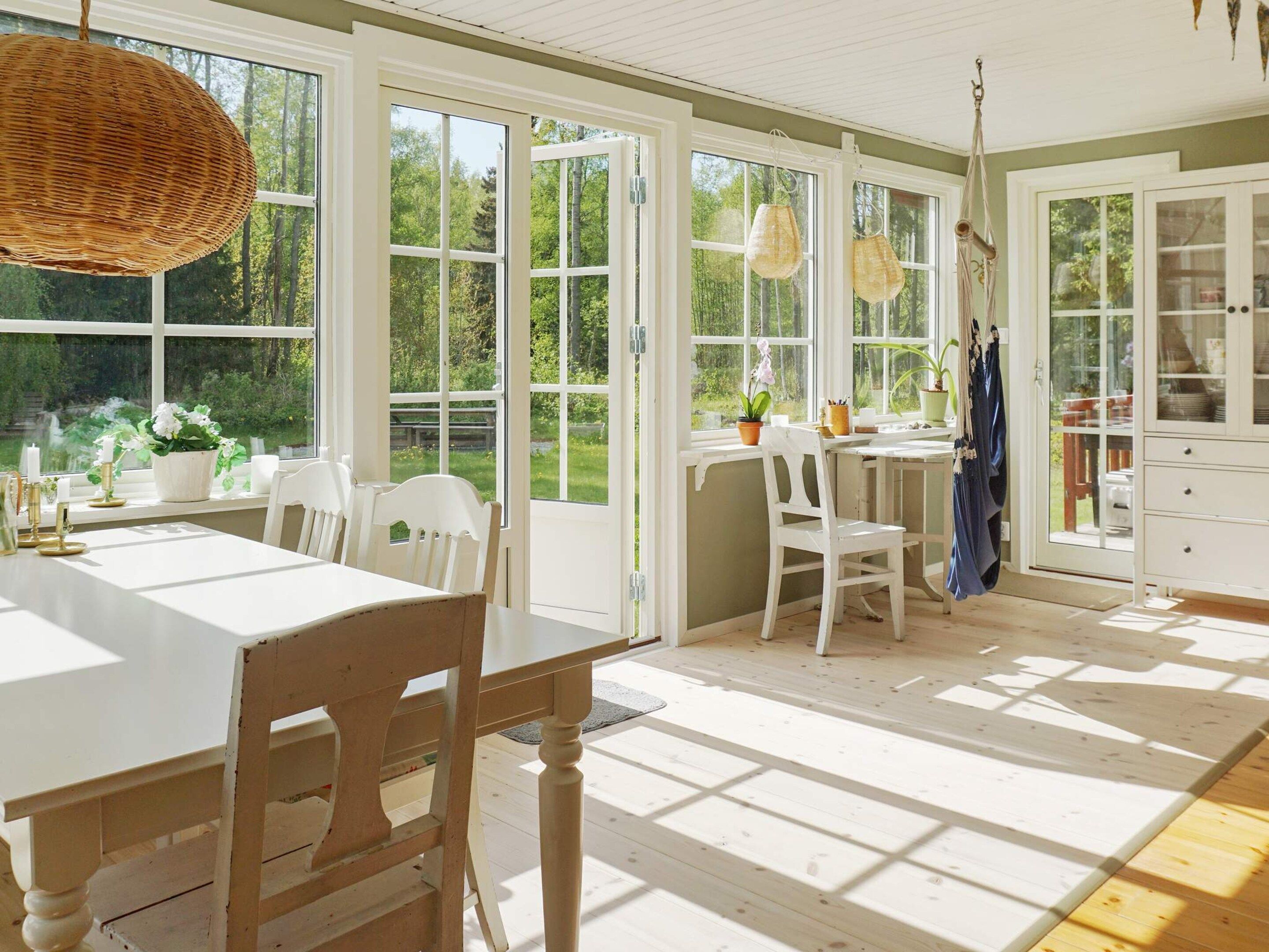 Una habitación luminosa con ventanas amplias, una mesa de comedor, sillas y una zona de cocina.