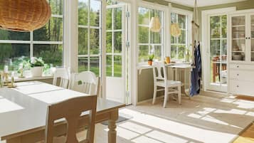 Una habitación luminosa con ventanas amplias, una mesa de comedor, sillas y una zona de cocina.