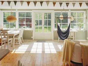 A room with a dining table, chairs, a hammock, and large windows. - 4 Star Holiday Home in Grisslehamn (Grisslehamn)