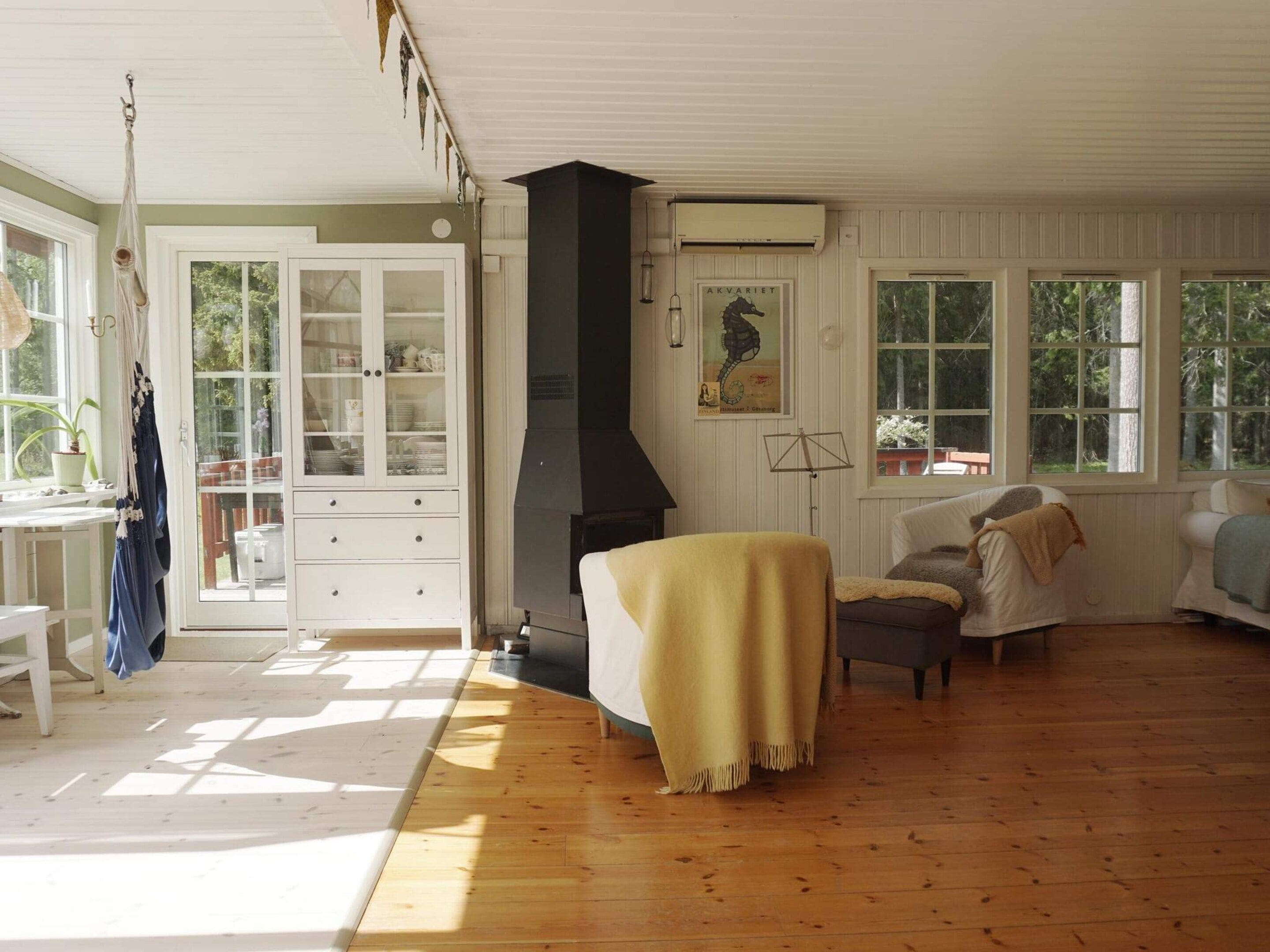 A spacious living room with a fireplace, wooden flooring, and large windows.