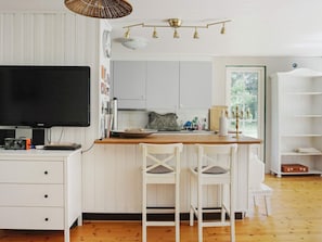A modern kitchen with white cabinetry, a wooden island, and a flat-screen TV. - 4 Star Holiday Home in Grisslehamn (Grisslehamn)