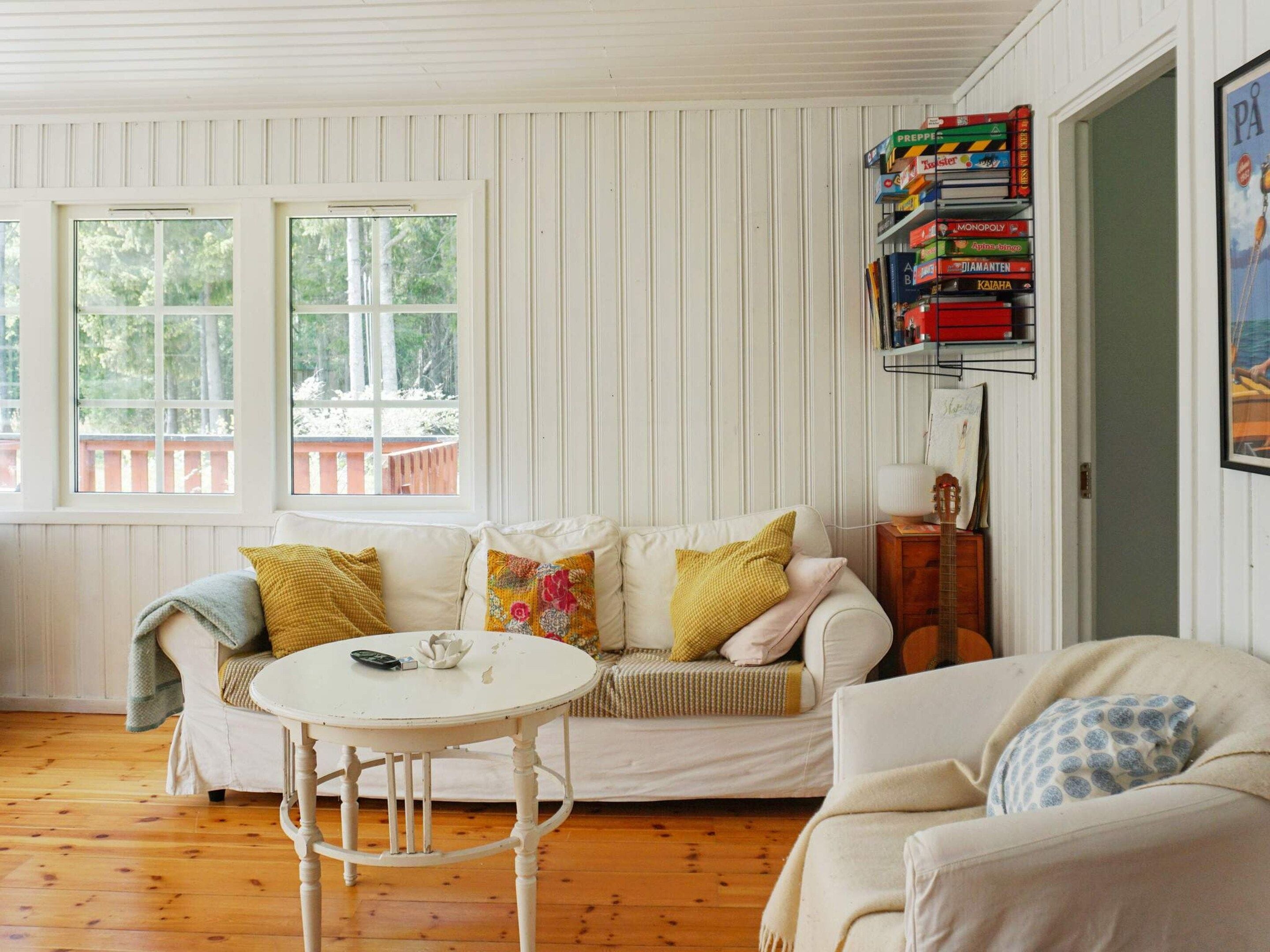 A cozy room with a white sofa, a round table, and a bookshelf filled with board games.
